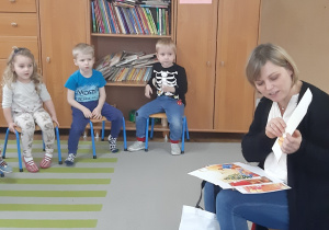 Dzieci słuchają czytanego przez bibliotekarkę opowiadania.